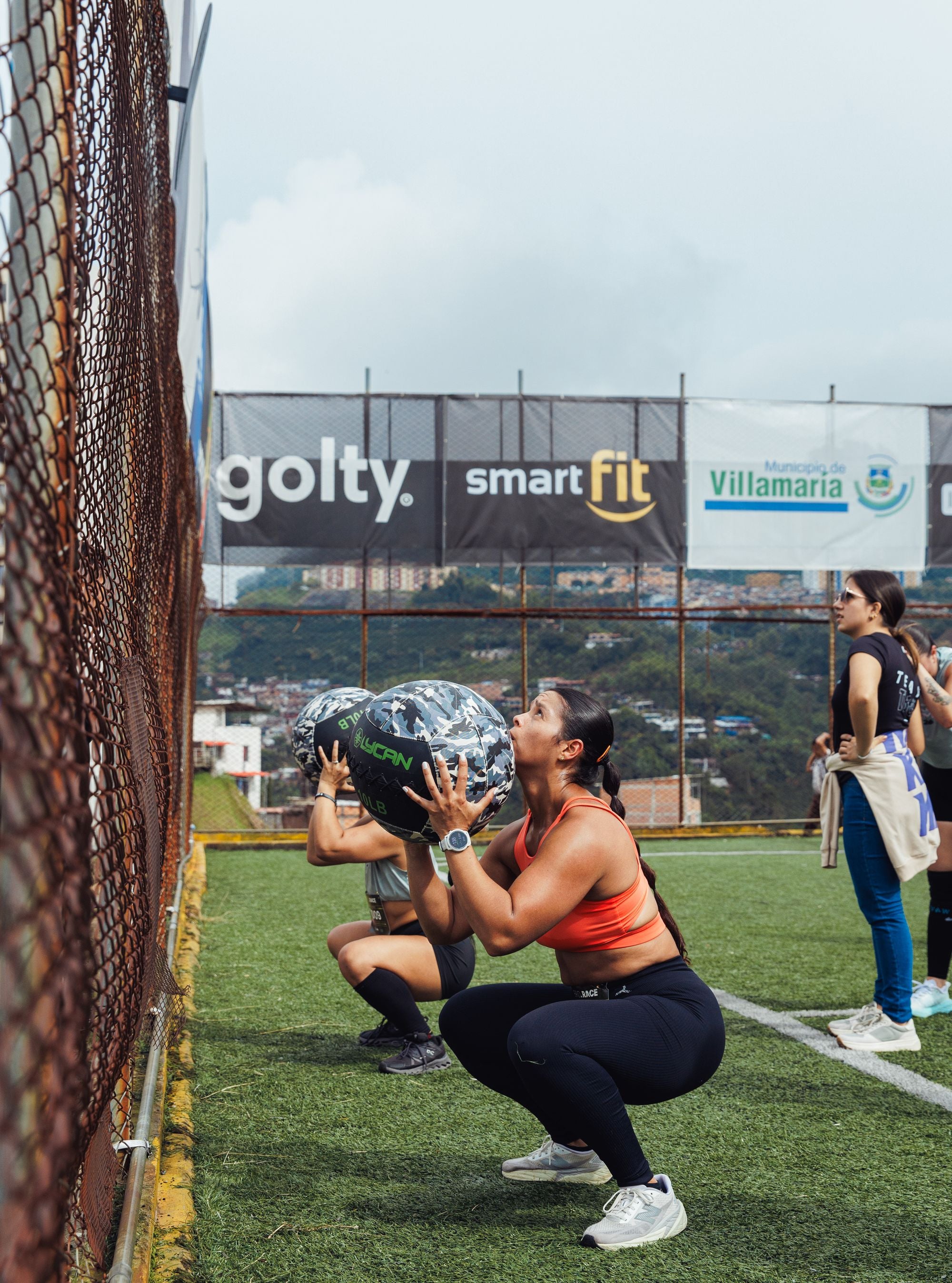 Groupe de femmes s'entraînant en extérieur avec des medicine balls, catégories HYROX